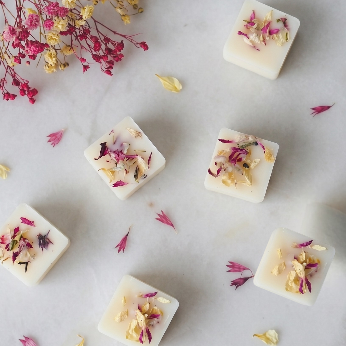 Floral sweet pea wax melt cube gently melting in a ceramic burner dish by Hideaway Home Fragrances releasing jasmine and hyacinth aromas