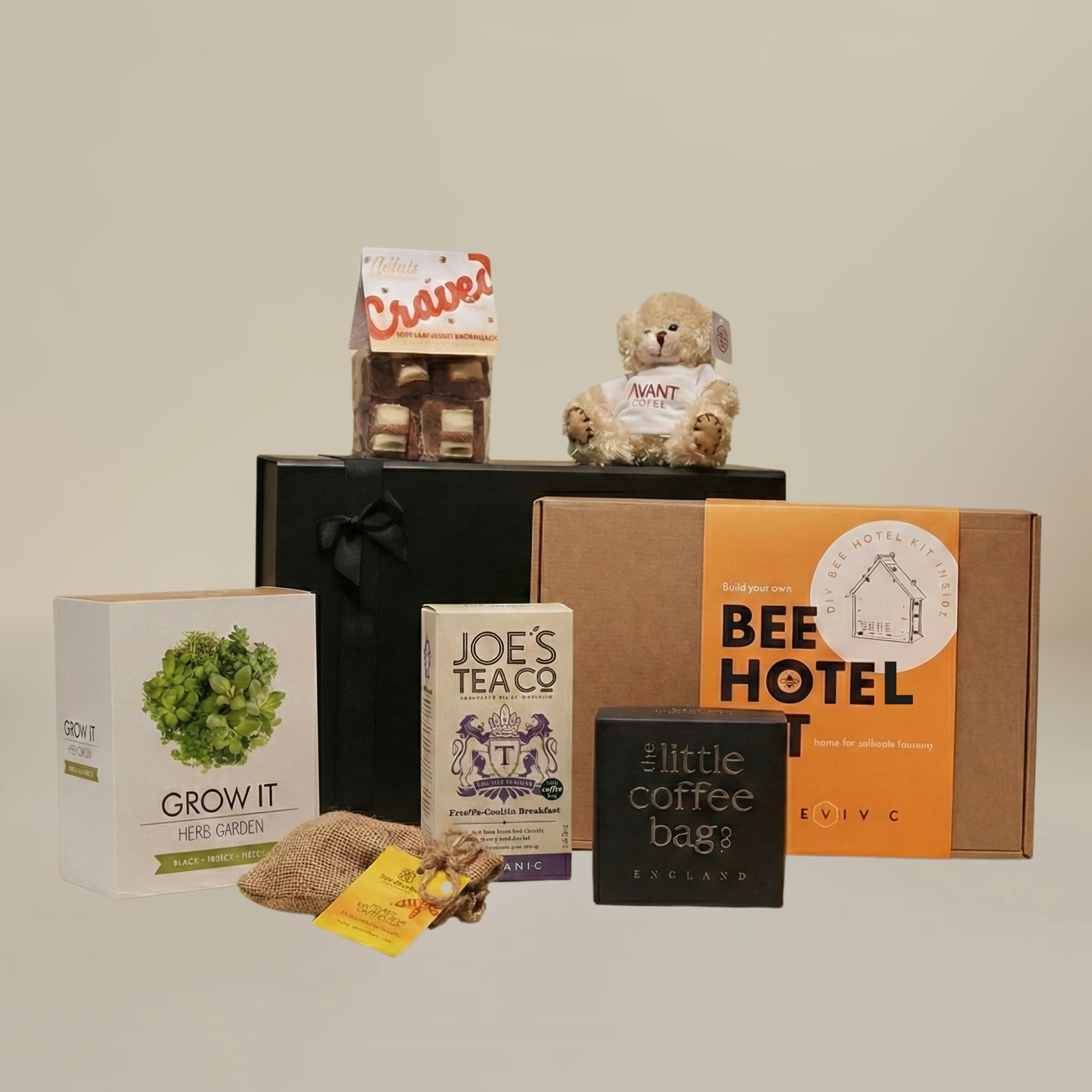 Gardening gift set flatlay with herb grow kit, biodegradable coffee bags, gourmet marshmallows, and wildlife friendly bee hotel.