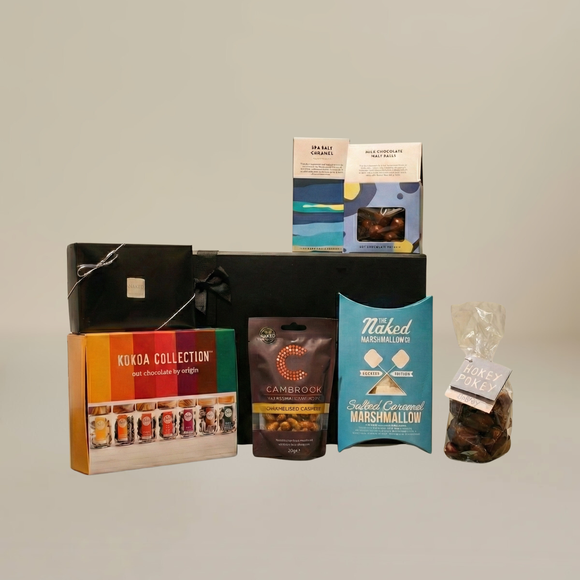  Luxury chocolate gift set flatlay with milk chocolate malt balls, artisan chocolate bar, caramelised peanuts, and hot cocoa collection.