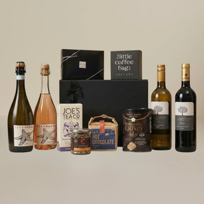 Gourmet wine and snack gift set with artisan chocolate, biodegradable coffee bags, caramelized peanuts, and Spanish wine bottles.