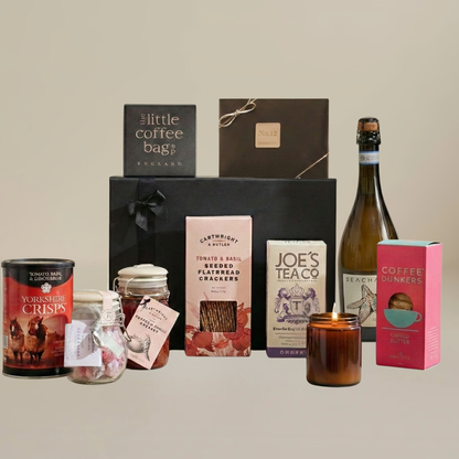 Luxury home gift set flatlay with coffee dunkers, artisan chocolates, chutney jar, flatbreads, and biodegradable coffee bags.