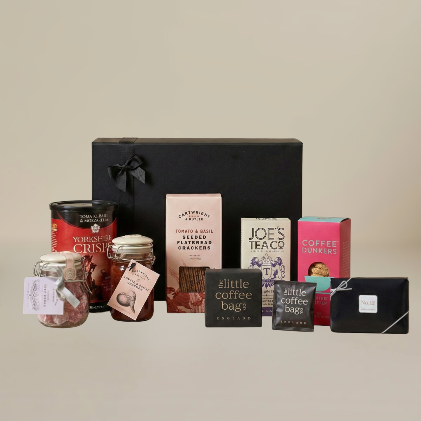 Luxury food gift set flatlay with artisan chocolates, jar of chutney, biodegradable coffee bags, and savoury flatbreads.