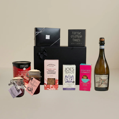 Luxury hamper flatlay with Yorkshire Crisps, artisan chocolates, biodegradable coffee bags, jar of chutney, and sparkling wine.