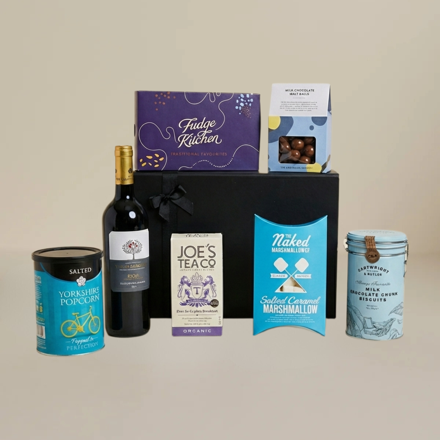 Luxury food and wine flatlay with milk chocolate malt balls, gourmet marshmallows, red wine bottle, and buttery biscuits.