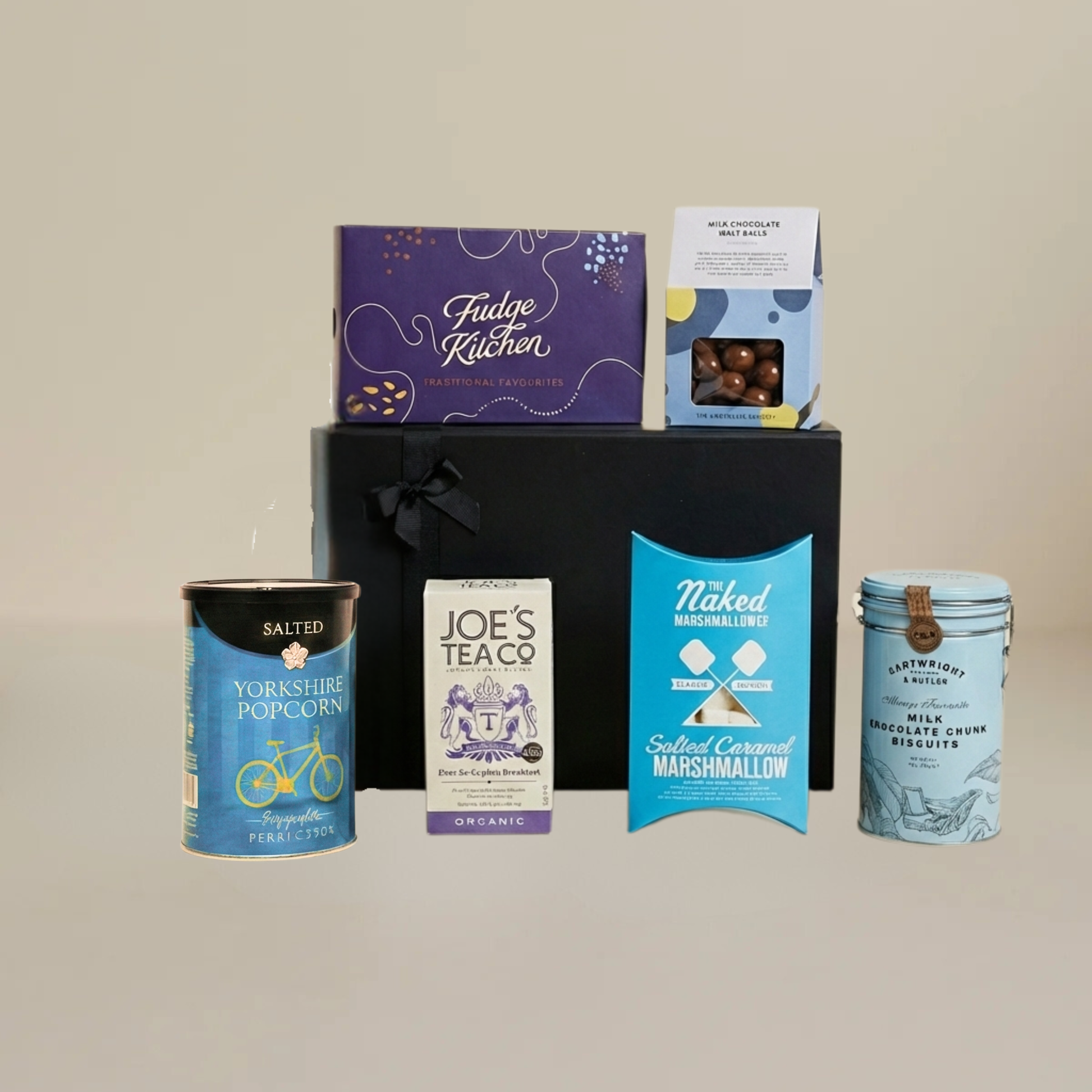 Luxury food gift set flatlay with milk chocolate malt balls, gourmet marshmallows, artisan popcorn, and biodegradable tea temples.