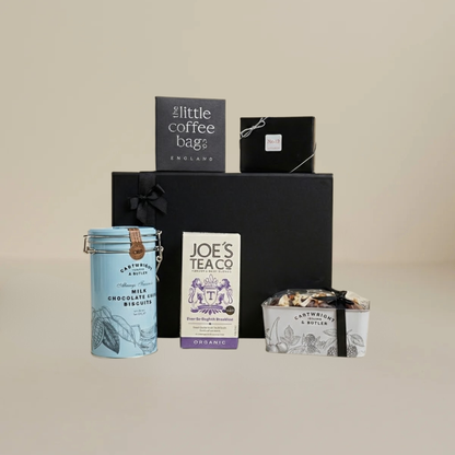 Afternoon tea gift set flatlay with No12 chocolates, biodegradable tea temples, butter biscuits, and chocolate cake tin.