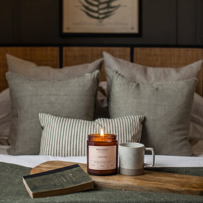 Soothing unwind amber glass jar candle styled on a cosy evening bedside table, Hideaway Home Fragrances