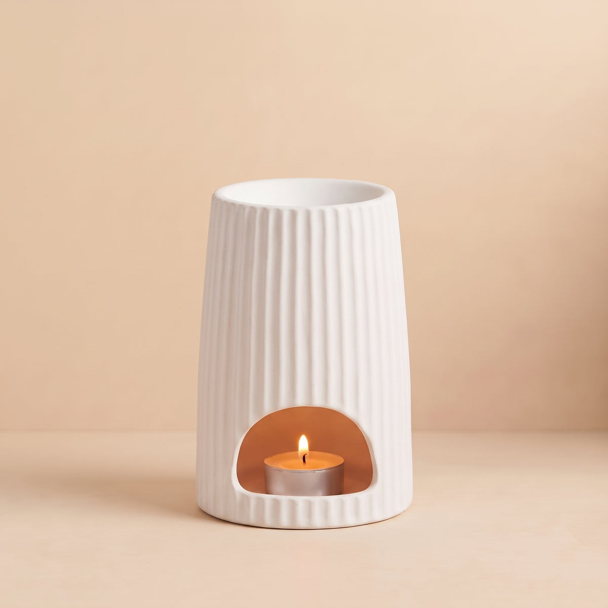 Warm glowing White Ribbed Ceramic Wax Melt Burner with lit tealight and melting wax tarts by Hideaway Home Fragrances