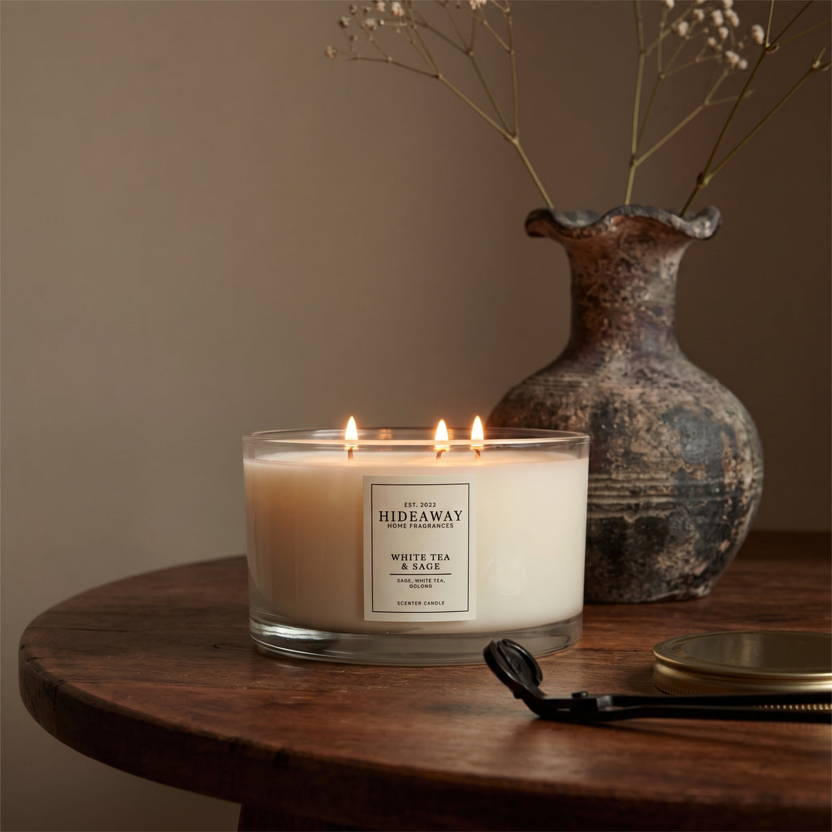 Hideaway Home Fragrances White Tea and Sage 3 wick candle burning on a kitchen island surrounded by fresh herbs for a clean home fragrance